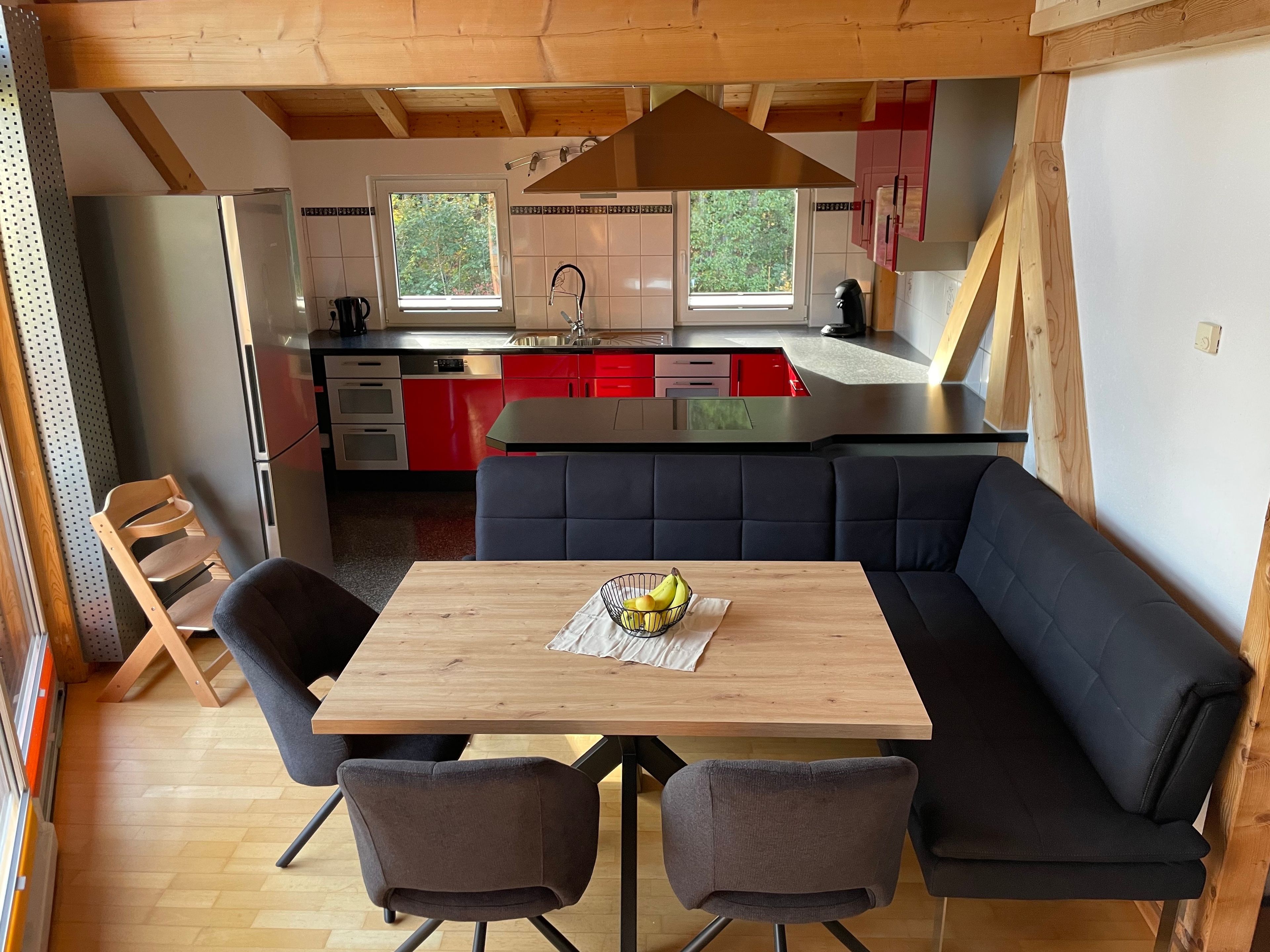 Une cuisine compacte dotée d’un îlot central, d’un coin repas avec une table et des chaises, et offrant une vue sur l’extérieur grâce à une fenêtre.