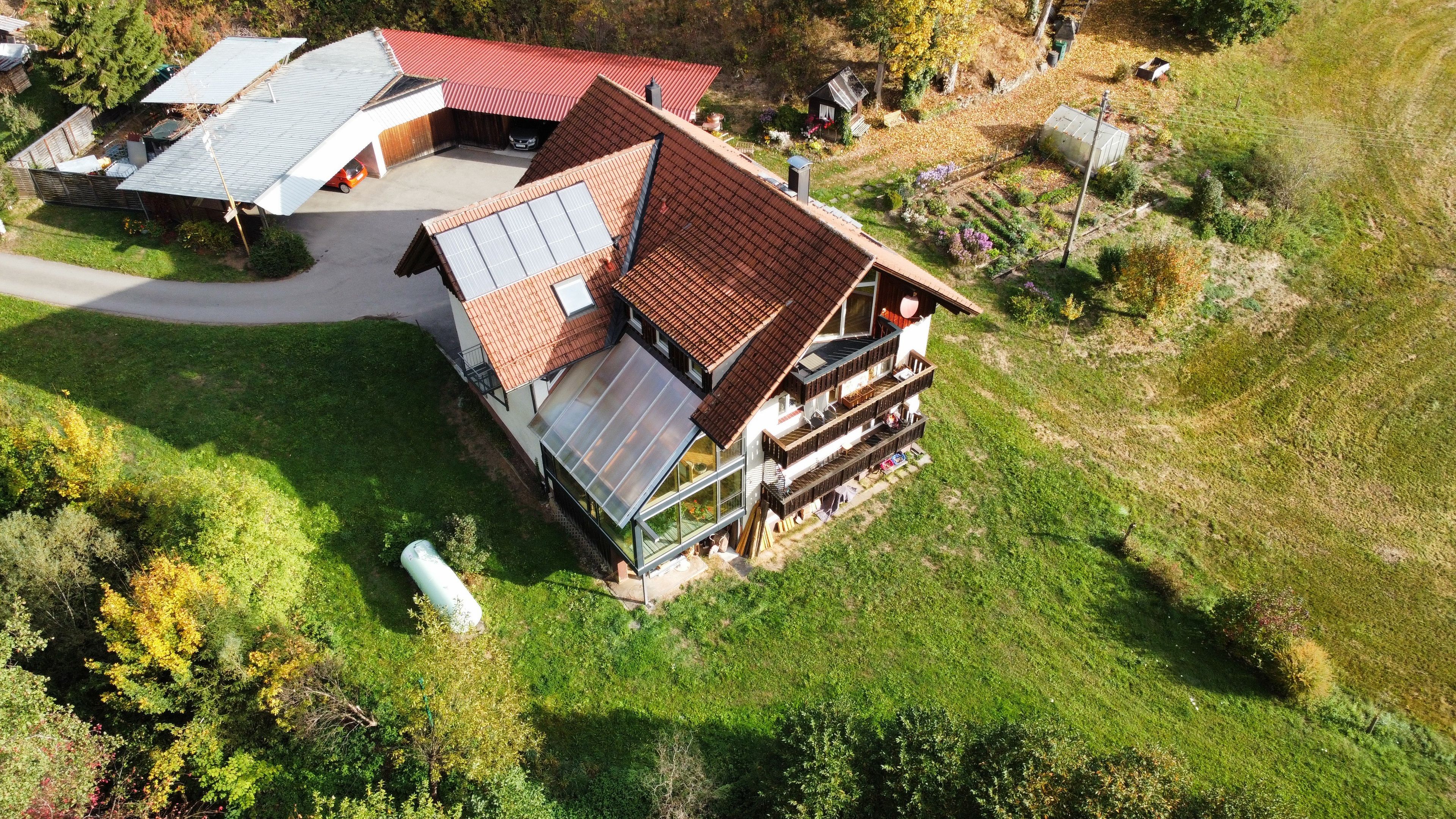 Ein mehrstöckiges Gebäude mit geneigtem Dach, einer großen Glasfassade und einem Balkon mit Sitzgelegenheiten.