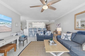Ein Wohnzimmer mit Deckenventilator, Fernseher, Sofa und Couchtisch.