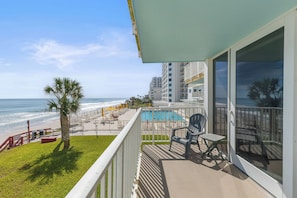A balcony with a view of the ocean and a pool area. - Smyrna Beach Club 218B 🌊 Oceanfront Condo with Private Balcony (New Smyrna Beach)