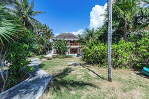 A tropical resort with a thatched-roof building, surrounded by palm trees and a well-maintained lawn. - Beachfront House With Private Pool in Tulum (Tulum)