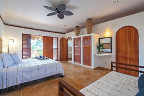 A bedroom with a bed, a desk, a ceiling fan, and a large window with shutters. - Beachfront House With Private Pool in Tulum (Tulum)