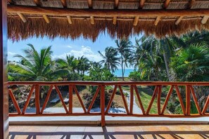 A covered outdoor area with a view of palm trees and the ocean. - Beachfront House With Private Pool in Tulum (Tulum)