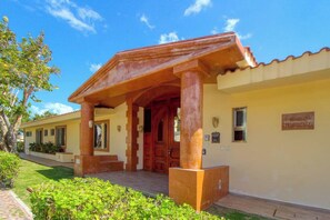A building with a covered entrance, a tiled roof, and a well-maintained lawn. - Beachfront Villa Private Chef, Pool & Transfer (Playa del Carmen)