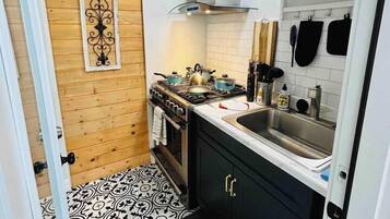 Cozinha compacta com fogão, pia e painéis de parede de madeira.