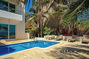 Ein Swimmingpool mit Liegestühlen und Palmen.