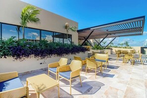 A rooftop terrace with outdoor seating, a pergola, and a view of the city skyline. - Chic Studio in Playa Centro, Rooftop Pool & Gym (Playa del Carmen)