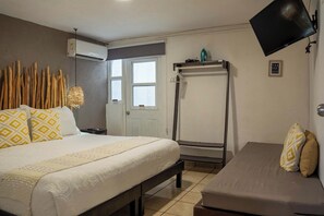 A hotel room with a bed, a bench, a TV, and a wall-mounted air conditioning unit. - Downtown Cancún Studio · Rooftop Terrace & Wifi (Cancun)