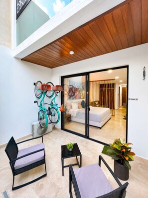 Ein modernes Wohnzimmer mit Balkon, einer Couch, einem Esstisch und einem Fahrrad.