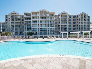 A hotel with a swimming pool, multiple balconies, and a covered area. - Destin Pointe Magnolia House #306 (Destin)