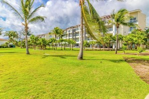 A hotel with multiple floors, a well-maintained lawn, and palm trees. - Mareazul Beachfront 2BR Pool & Sea Views (Playa del Carmen)