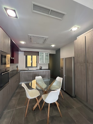 Una cocina moderna con una isla central, sillas blancas y electrodomésticos integrados.