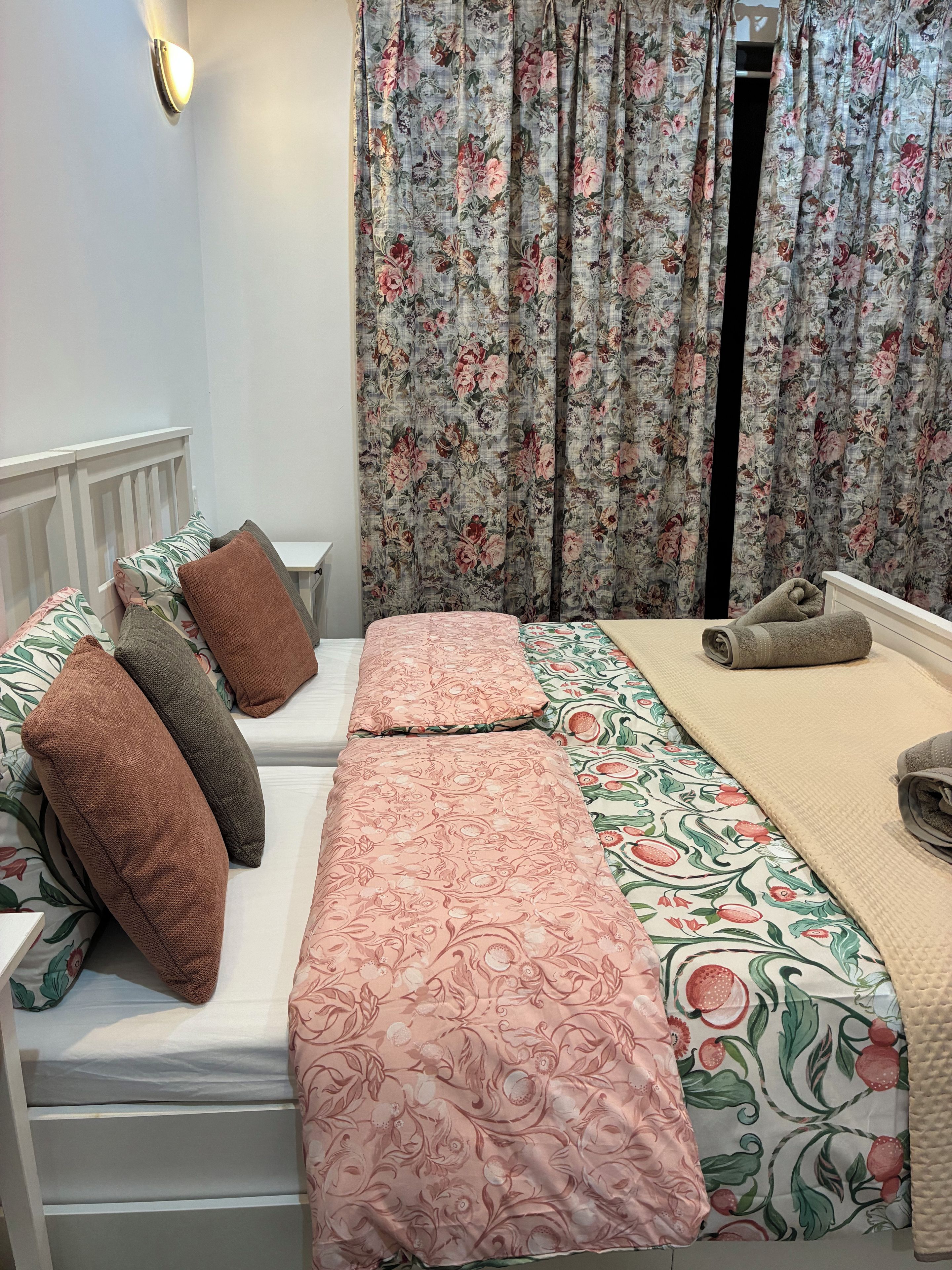 Un dormitorio con cama, almohadas, mesita de noche y cortinas.