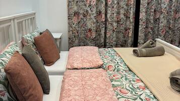 Un dormitorio con cama, almohadas, mesita de noche y cortinas.