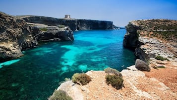 A coastal landscape with rocky terrain and clear blue waters.