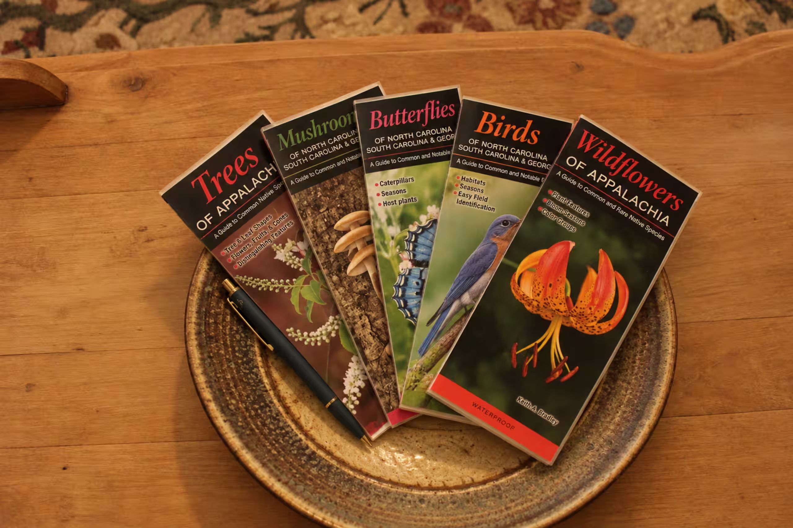 Verschillende vogelgidsen en andere natuurboeken op een houten tafel.
