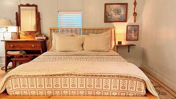 A bedroom with a wooden bed, a dresser, a mirror, and wall-mounted lamps.