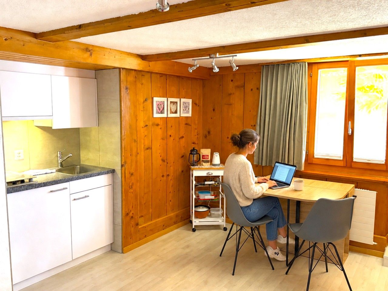 Une cuisine de taille réduite comprenant un évier, des placards et un coin repas avec une table et des chaises.