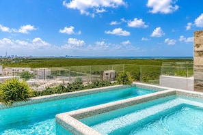 A rooftop infinity pool with a clear view of the ocean and city skyline. - Ocean View Condo w/ Luxury Pool Rooftop Access (Cancun)