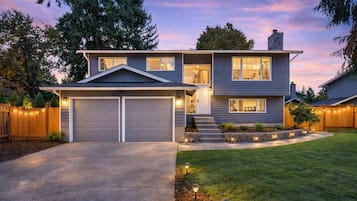 A modern two-story house with a garage, a well-maintained lawn, and a wooden fence.