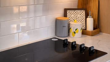 A modern kitchen with a stainless steel microwave, a black induction cooktop, and a white tiled backsplash.