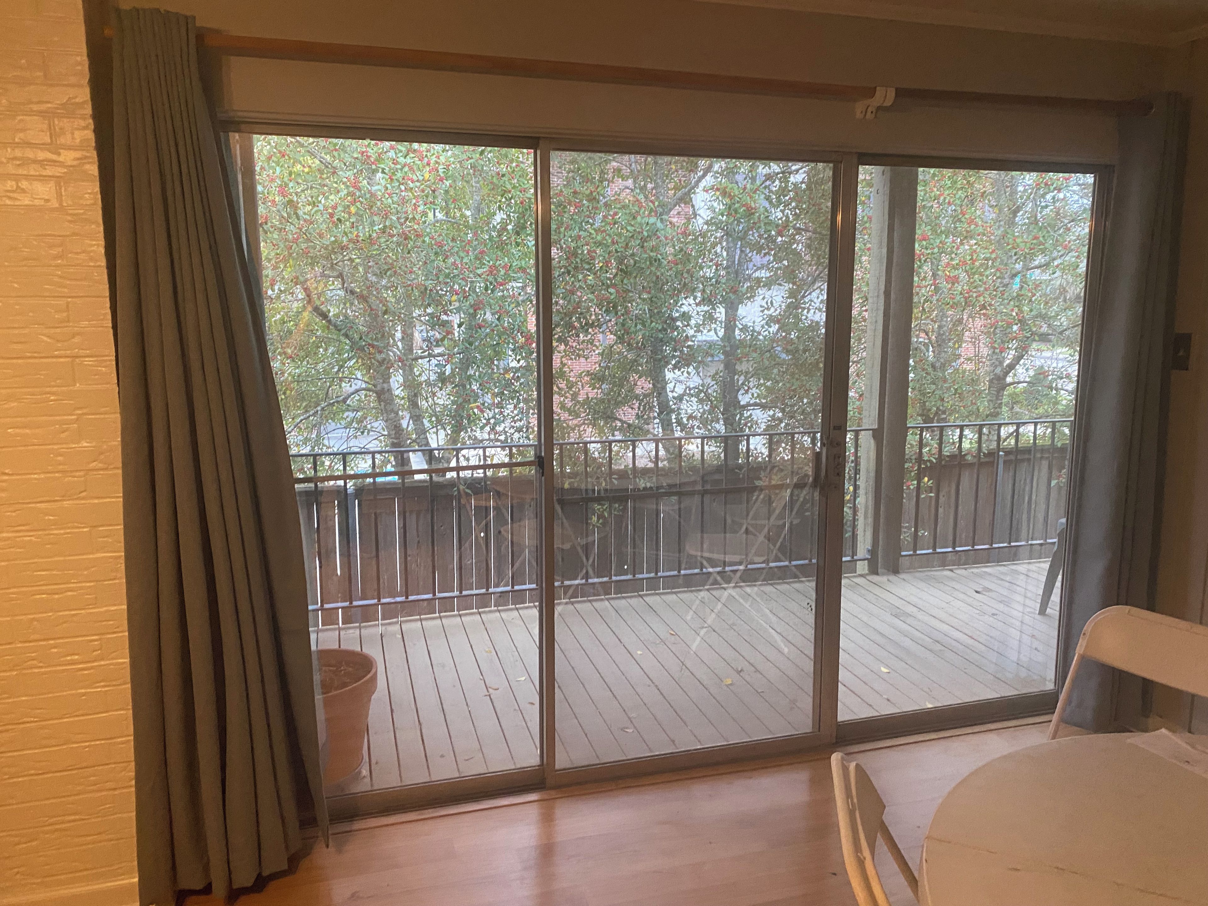 Una habitación con un ventanal corredero que da a una terraza exterior con barandilla de madera.