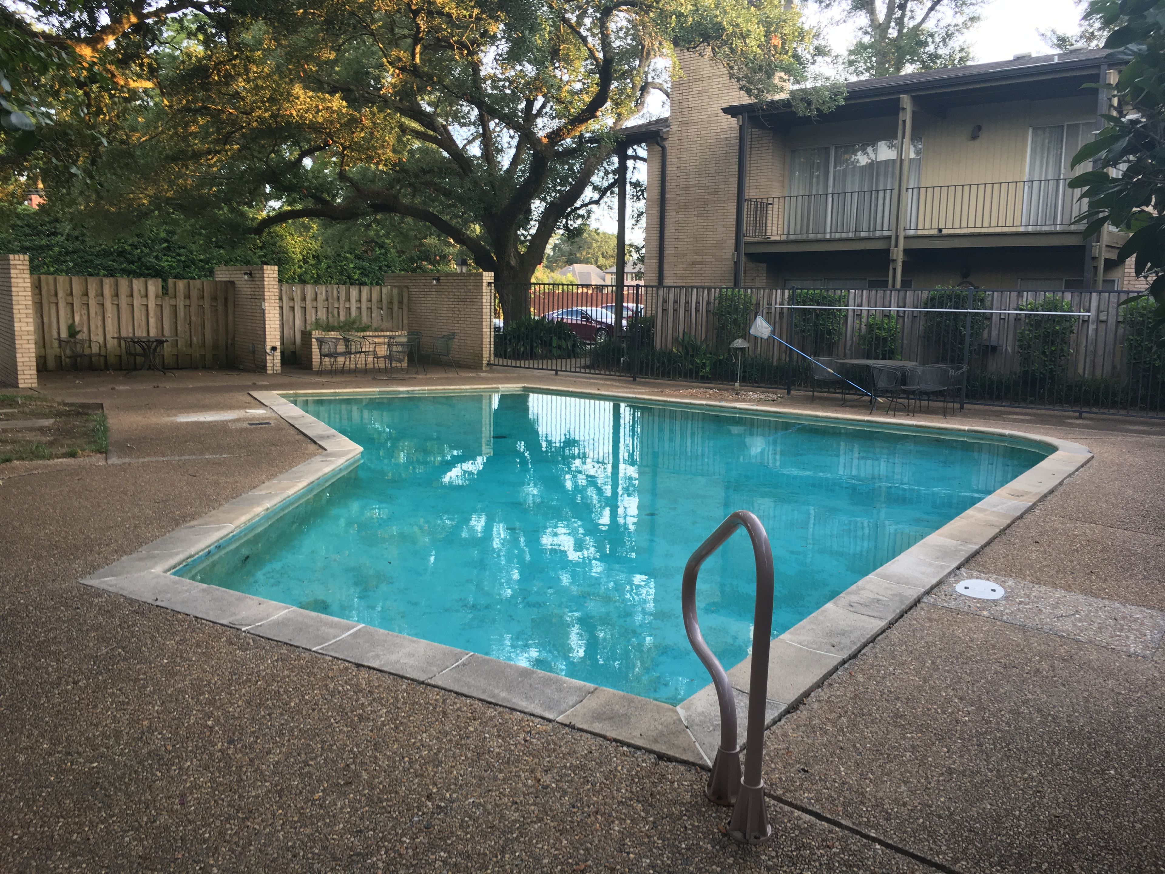 Piscina rectangular con una escalera metálica en el centro, rodeada por una solana de hormigón.
