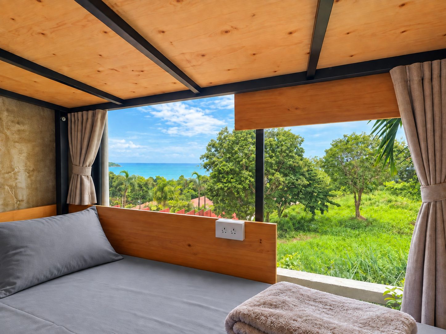 A bedroom with a bed, a window with curtains, and a view of greenery and the sea.