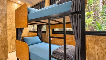 Una cama litera con colchón azul, almohadas grises y cortinas.