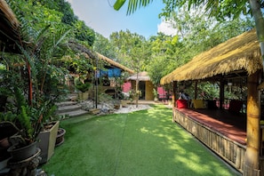 A lush garden with a thatched-roof structure, potted plants, and a well-maintained lawn. - Smith & Appy Hillside Seaview Hostel (Chang Wat Surat Thani)