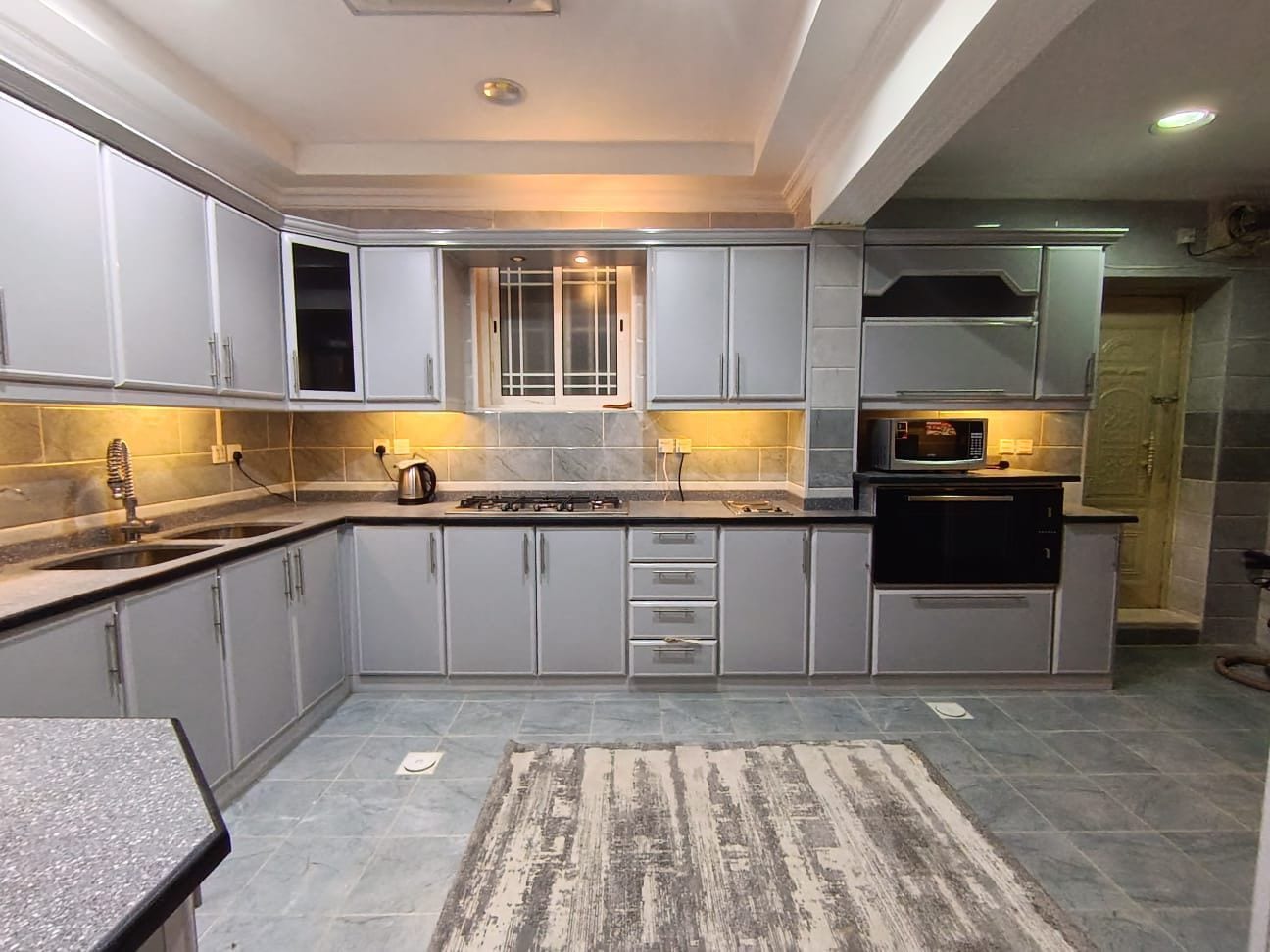 A modern kitchen with grey cabinets, a gas stove, and a microwave.