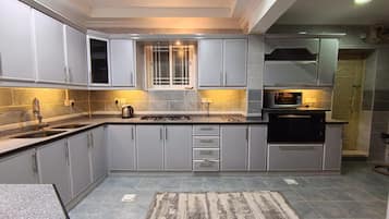 A modern kitchen with grey cabinets, a gas stove, and a microwave.