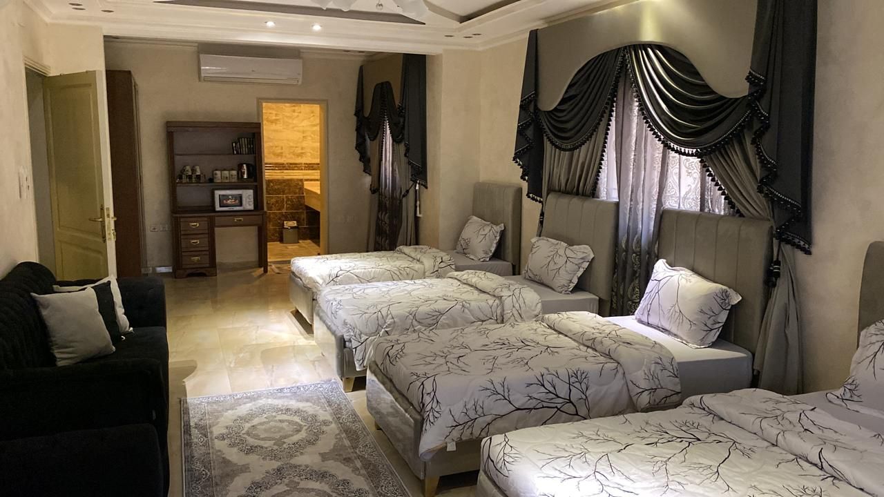 Une chambre d’hôtel comprenant un canapé, deux lits avec la même literie, un bureau et une armoire.