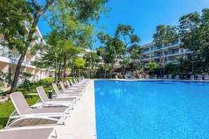 A swimming pool with lounge chairs and a building in the background. - Playacar 1BR Condo Pools, Balcony & Wifi (Playa del Carmen)