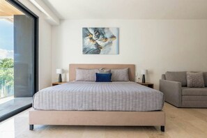 A modern bedroom with a large bed, a sofa, and a painting on the wall. - Studio Rooftop Pool & Gym, Steps to Beach (Playa del Carmen)