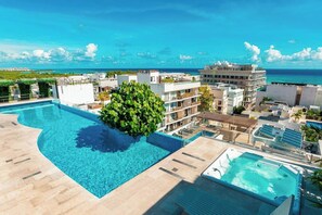 A rooftop swimming pool with a view of the ocean and cityscape. - Studio Rooftop Pool & Gym, Steps to Beach (Playa del Carmen)