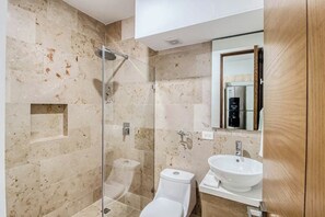 A modern bathroom with a glass-enclosed shower, a white toilet, and a sink with a mirror above it. - Studio With Rooftop Pool, Jacuzzi & Ocean Views (Playa del Carmen)