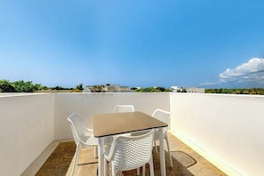 A rooftop terrace with a table and chairs, a clear sky, and distant buildings. - Stylish Studio Near Akumal - Rooftop Pool & Wifi (Akumal)