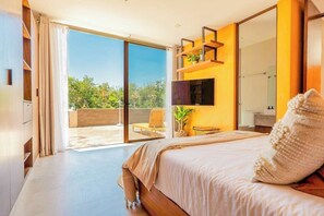 A bedroom with a large bed, a sliding glass door leading to a balcony, and a mounted TV. - Xpu-ha Villa Private Jacuzzi & Beach (Xpu-Ha)