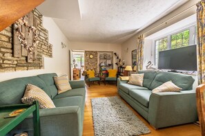 Ein gemütliches Wohnzimmer mit zwei grünen Sofas, einem Holztisch und einer Steinwand.