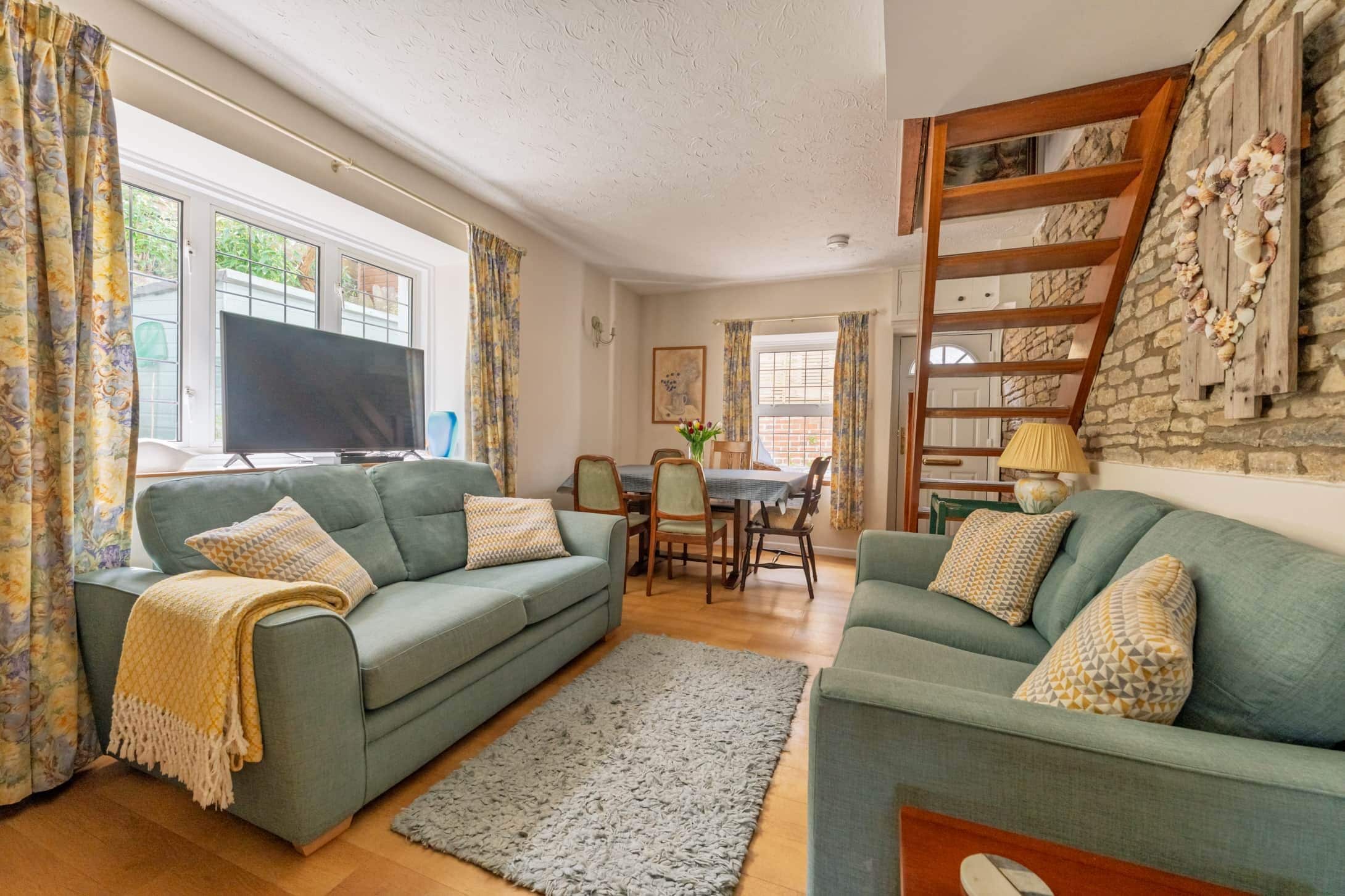 A living room with two sofas, a TV, and a dining area with chairs and a table.