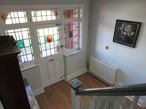 A staircase leading to a landing with a white door and stained glass windows.