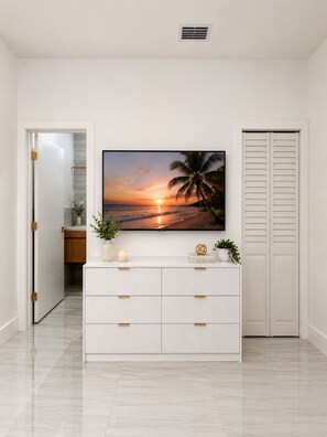 Un corridoio con un armadietto bianco, un quadro raffigurante un tramonto e una porta chiusa.