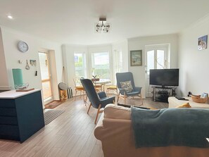 A living room with a sofa, a television, and a dining area with a table and chairs. - 3 Seascapes
A bright and modern apartment with lovely views towards Swanage Bay. (Swanage)