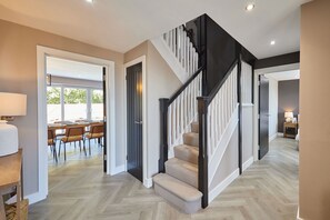 Ein modernes Interieur mit Treppe, Holzboden und Essbereich mit Stühlen und Tisch.