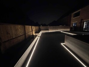 Eine Dachterrasse mit Holzboden, einer gewölbten Mauer und einem Gebäude mit Fenstern.