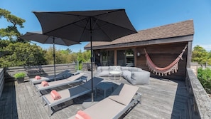 Eine Terrasse mit Gartenmöbeln, darunter Liegestühle und eine Couch, sowie einer Hängematte.