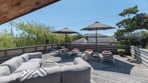 Une terrasse aménagée avec du mobilier d’extérieur, notamment des canapés et des tables, et dotée de deux parasols pour créer de l’ombre.