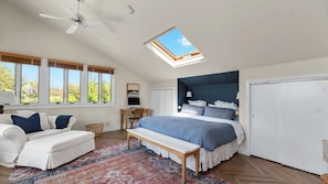 A bedroom with a large bed, a ceiling fan, a skylight, a desk with a chair, and a couch. - Beautifully Renovated & Stylish 5 BR Home in Ocean Beach With Pool Just One... (Ocean Beach)