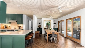 Eine moderne Küche mit einer zentralen Kochinsel, Barhocker und einem Essbereich mit Holztisch und Stühlen.